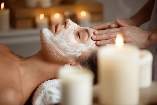 Young beautiful brunette girl in mask for face relaxing in spa salon. Copy space.